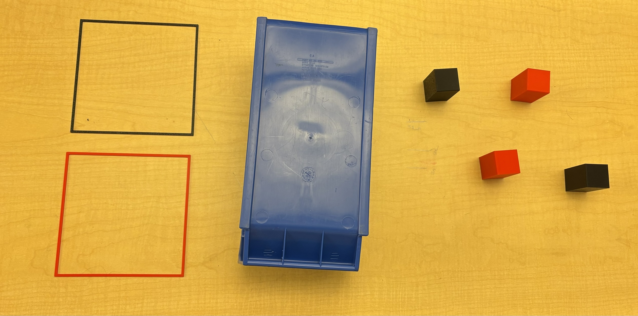 Top-down view: red and black cubes, blue obstacle bin, and two drop-off zones